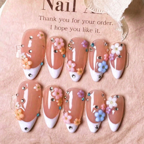 Kunstnagelset mit zarten Blumenverzierungen und funkelnden Strasssteinen Karnz