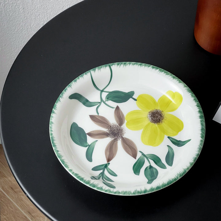 Tiefer Porzellanteller mit floraler Randornamentik und kontrastierendem Innenspiegel