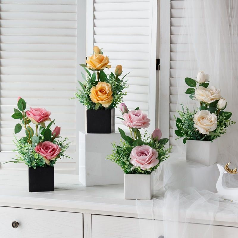 Lebensechte Blumenarrangement in dekorativem quadratischen Pflanzgefäß
