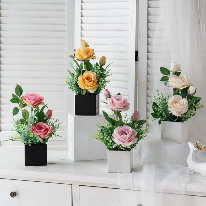 Lebensechte Blumenarrangement in dekorativem quadratischen Pflanzgefäß