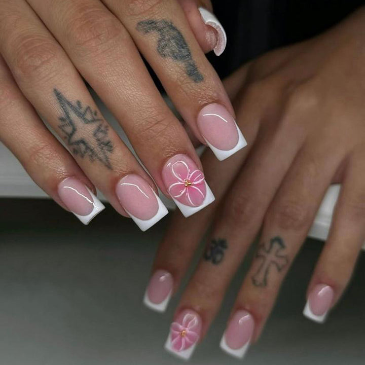 Kunstvolle Nagelkunst mit zarten Blüten und eleganter French-Spitze Karnz