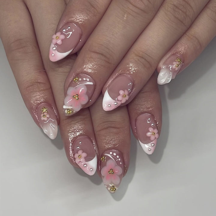 Kunstvolle Nagelverlängerungen mit Blütenmuster und Glitzerakzenten Karnz