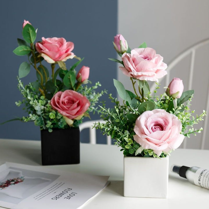 Lebensechte Blumenarrangement in dekorativem quadratischen Pflanzgefäß