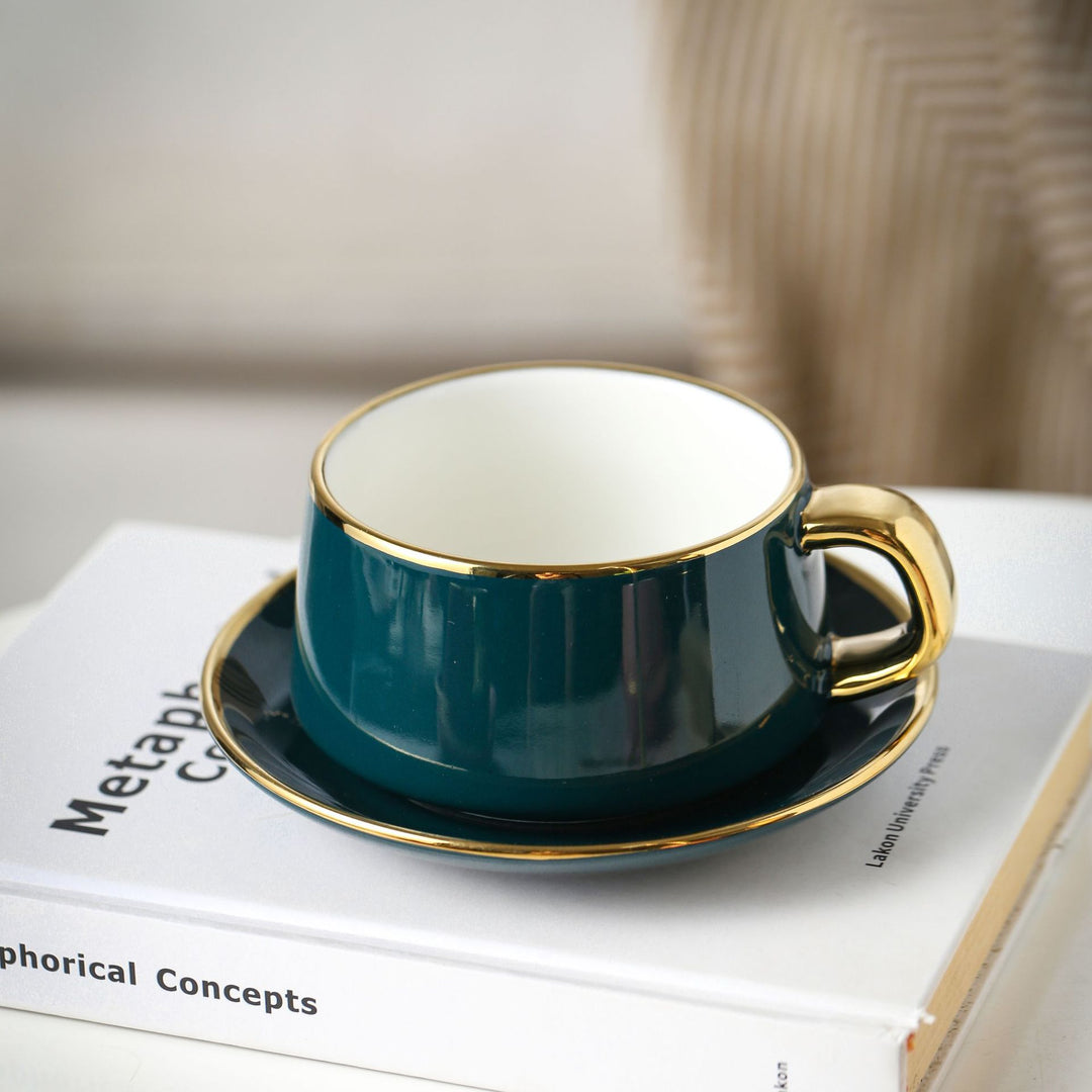 Elegante Porzellan-Tasse mit Untertasse und skulpturellem Goldhenkel