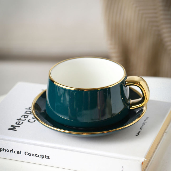 Elegante Porzellan-Tasse mit Untertasse und skulpturellem Goldhenkel