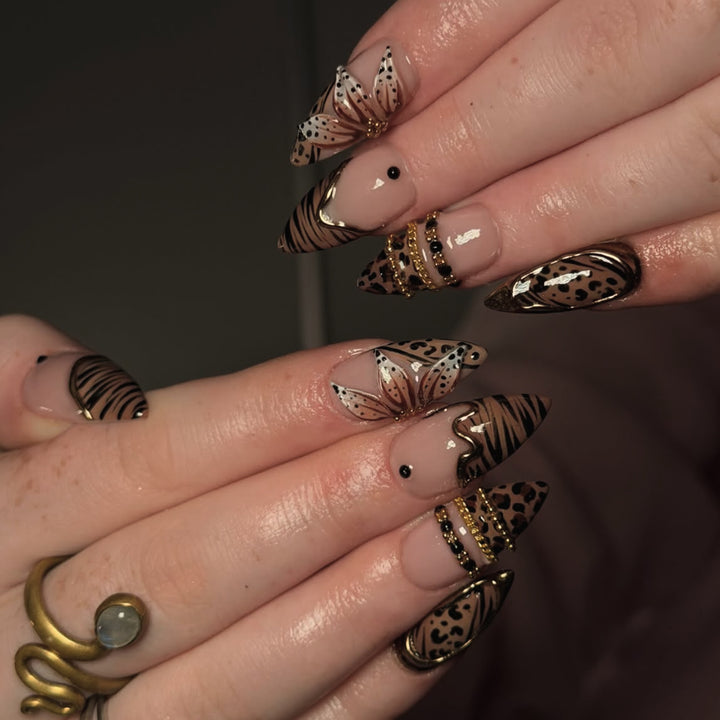 Kunstvoller Stiletto-Nagel mit floralen Akzenten und Goldverzierungen Karnz