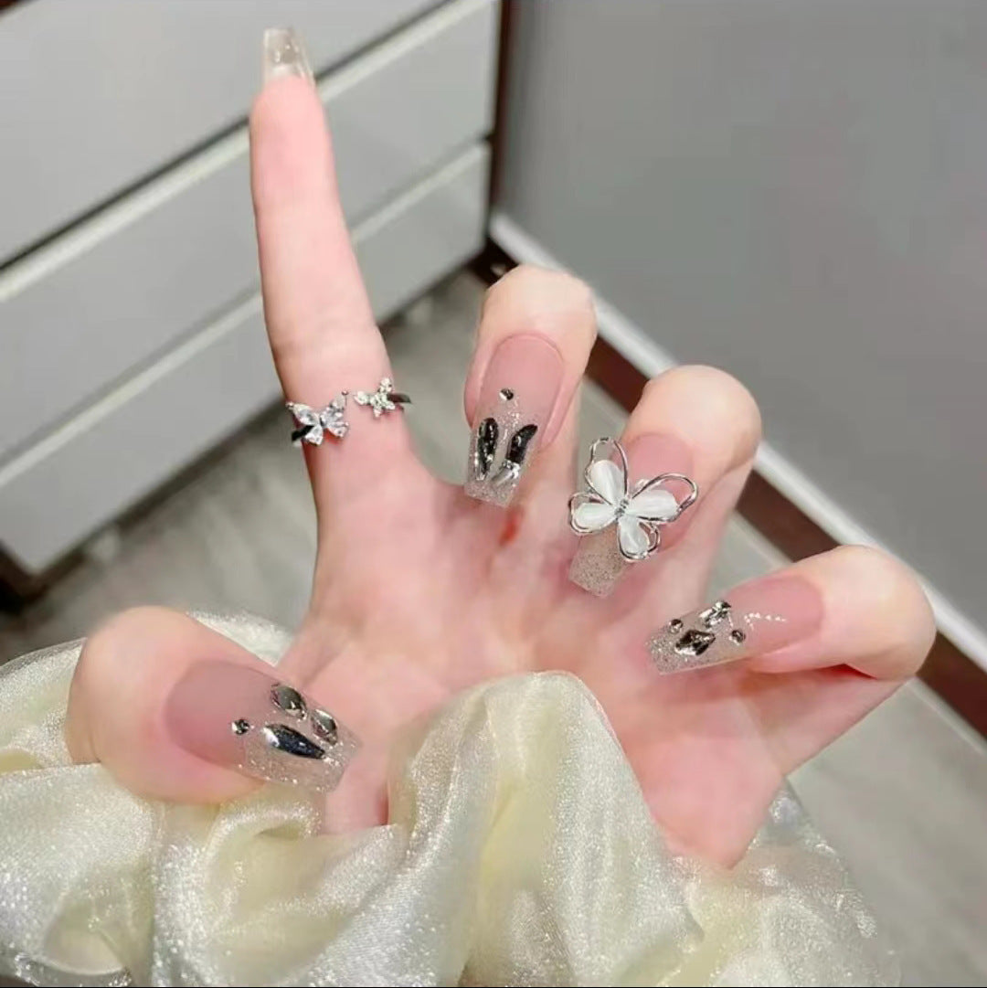 Kunstvolle Nagelkunst mit Glitzer- und Schmetterlingselementen Karnz