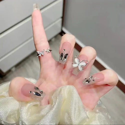 Kunstvolle Nagelkunst mit Glitzer- und Schmetterlingselementen Karnz