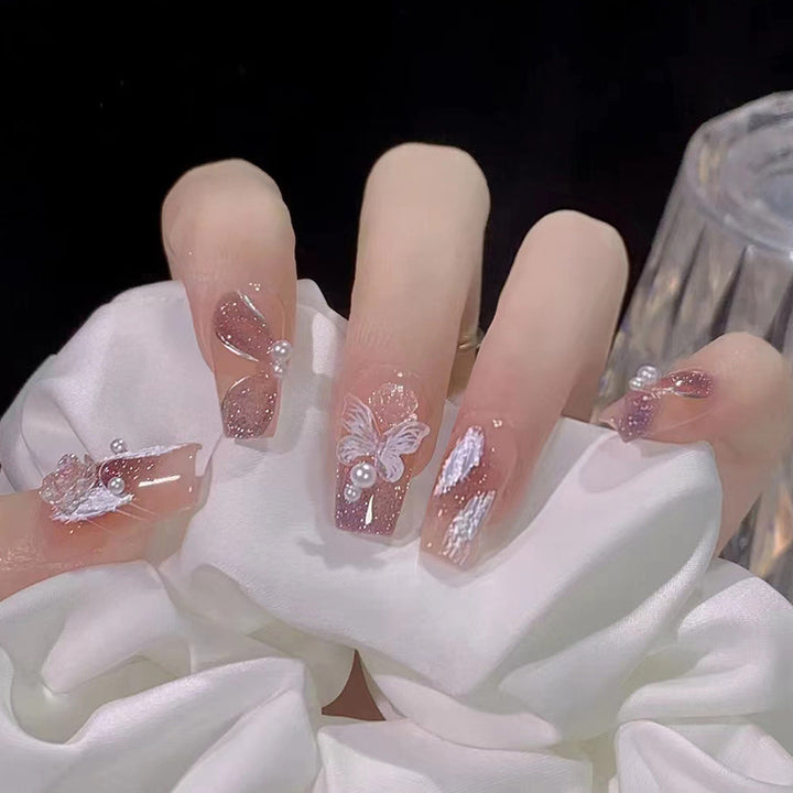 Kunstvolle Nagelkunst mit Schmetterlings- und Perlendetails Karnz