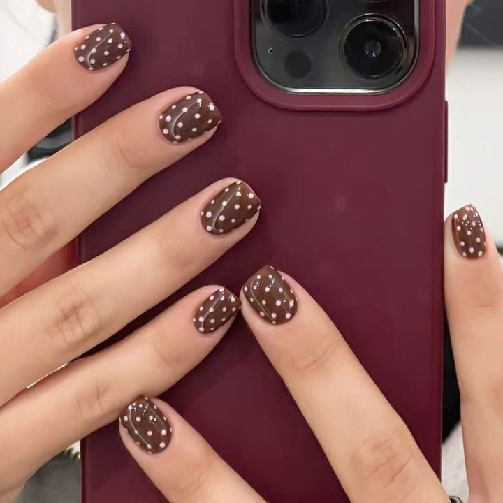 Kunstnagelset mit stilvollen Schokoladenflecken und eleganten Punkten Karnz