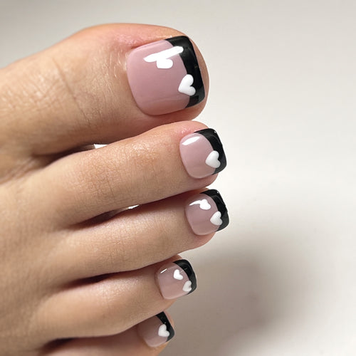 Kunstvolle Fußnagelgestaltung mit Herzmotiven und modernem Schwarz-Weiß-Design Karnz