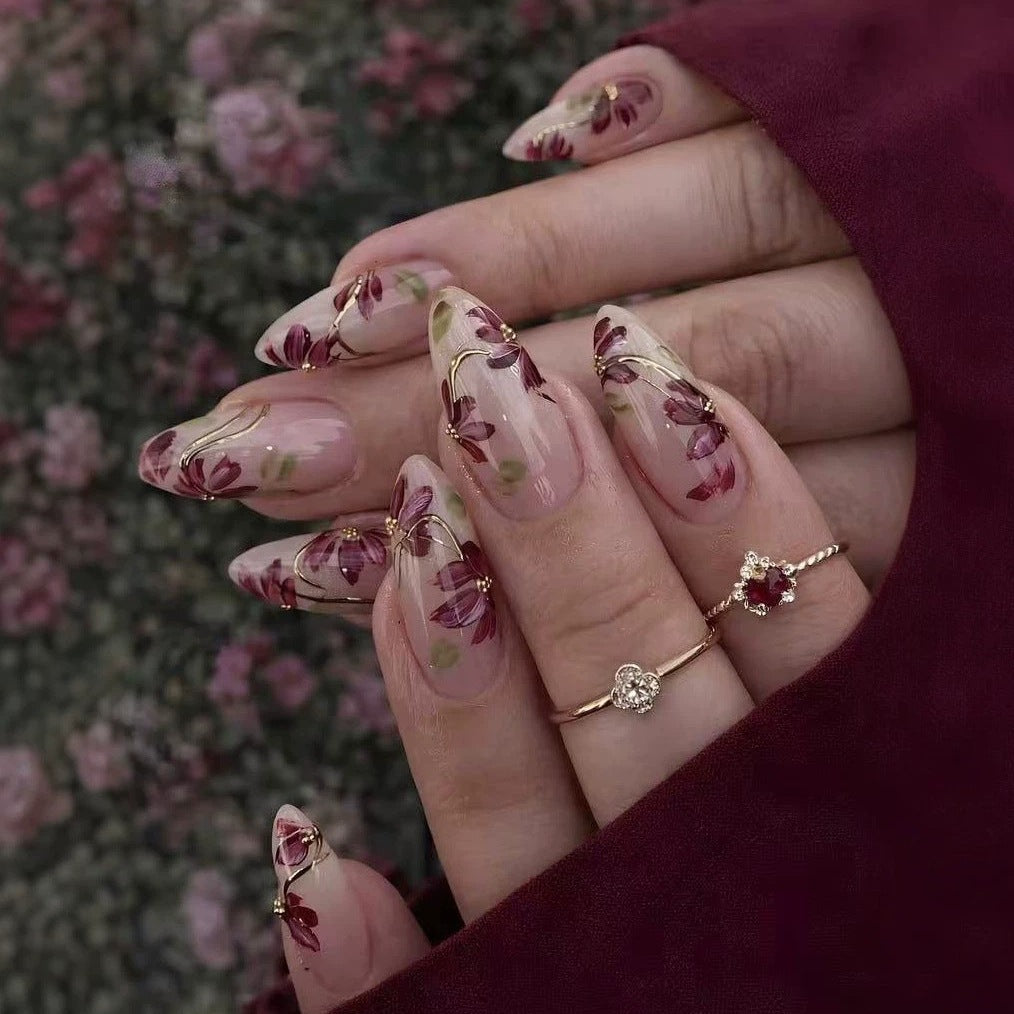 Kunstnagelset mit floralen Mustern und goldenen Akzenten Karnz