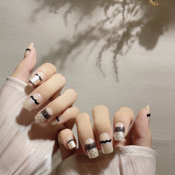 Künstlerisches Press-On-Nageldesign mit Spitze und Punkten