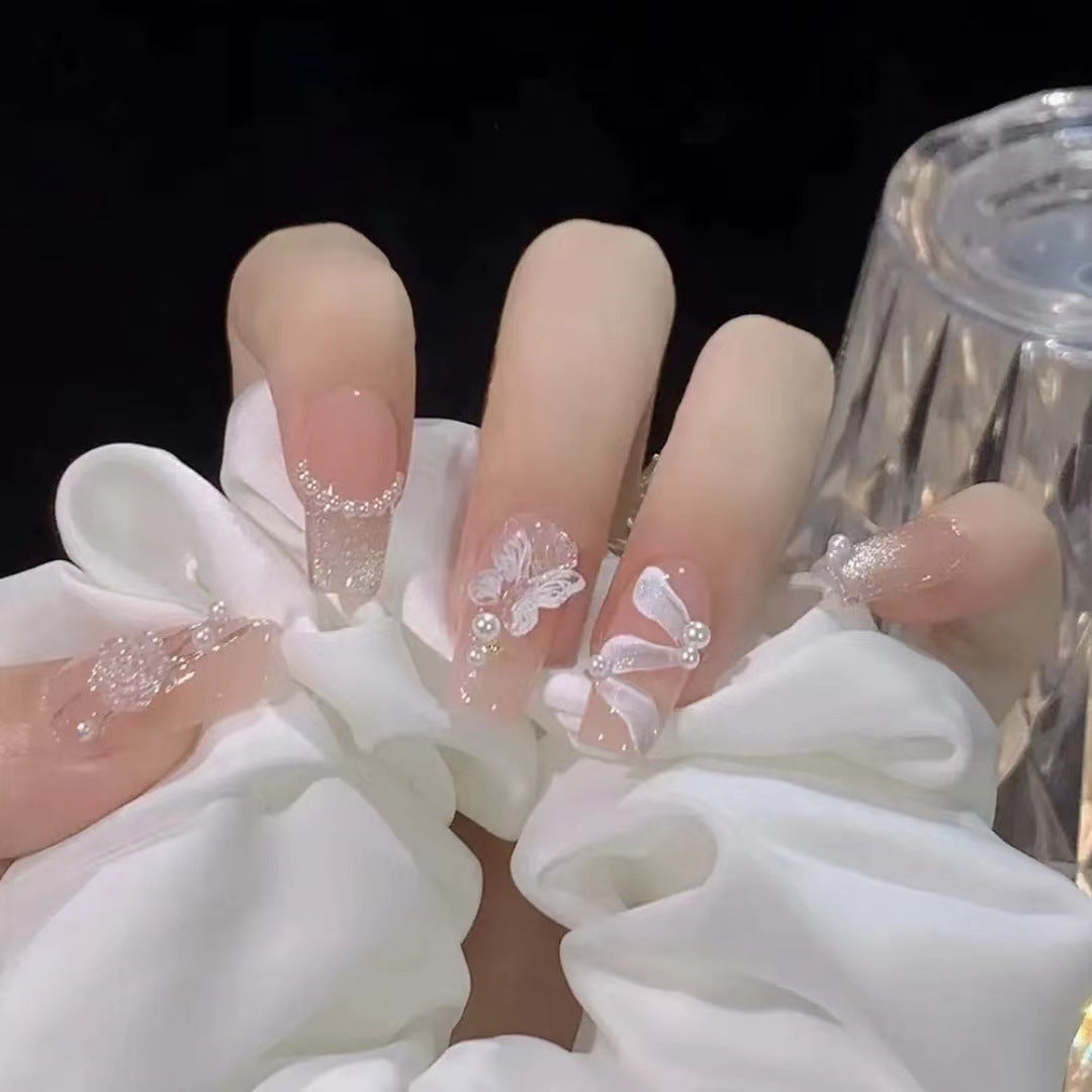 Kunstvolle Nagelkunst mit Schmetterlings- und Perlendetails Karnz