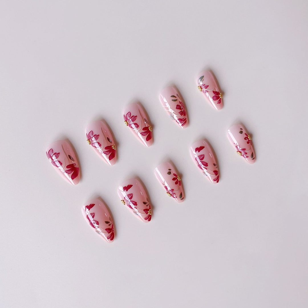 Kunstnagelset mit floralen Mustern und goldenen Akzenten Karnz