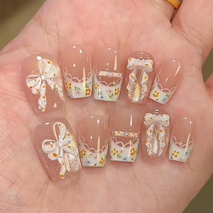 Kunstvolle Nagelverlängerungen mit floralem Design und Schleifenakzenten Karnz