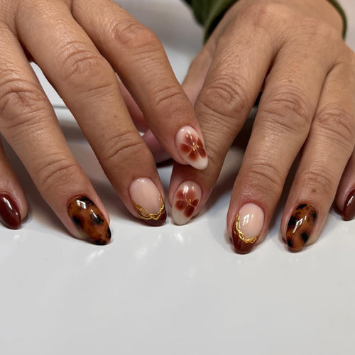Kunstvolle Acryl-Nägel mit floralen Verzierungen und Glitzerakzenten Karnz