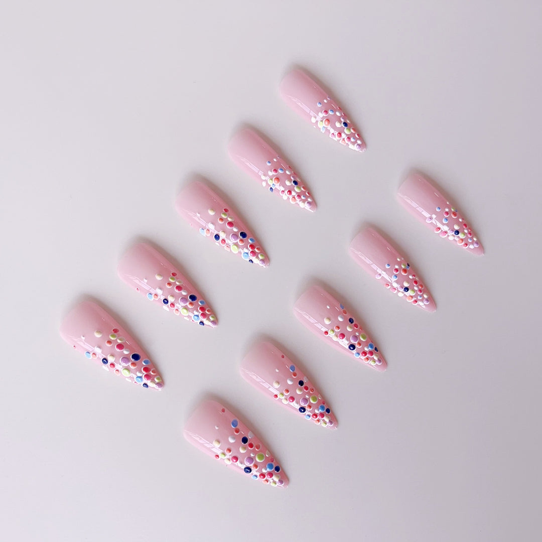 Kunstnagelset mit bunten Glitzerpunkten und eleganten Spitzen Karnz