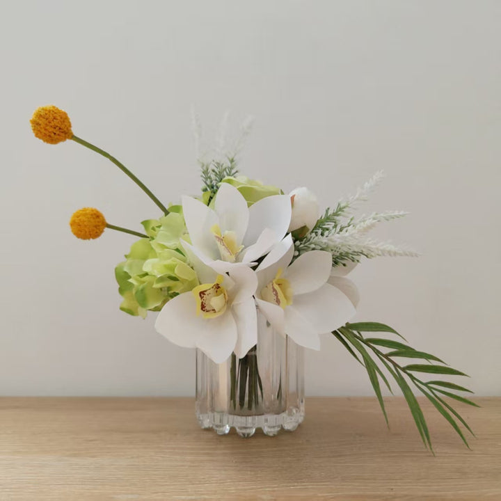 Lebensechte Blumenarrangement mit Orchideen und Grünpflanzen