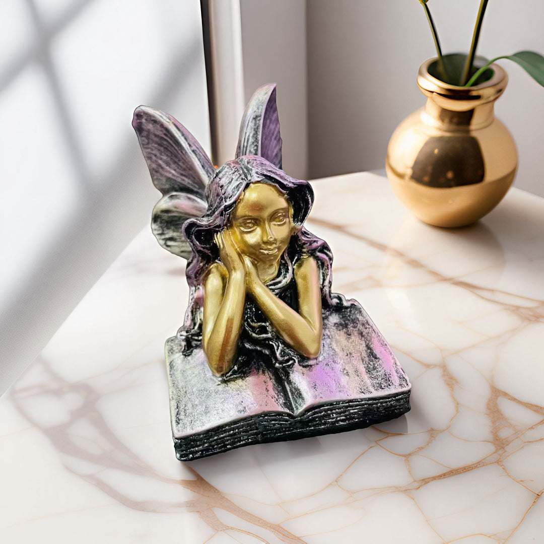 Feenfigurine, die auf Büchern sitzt, Karnz