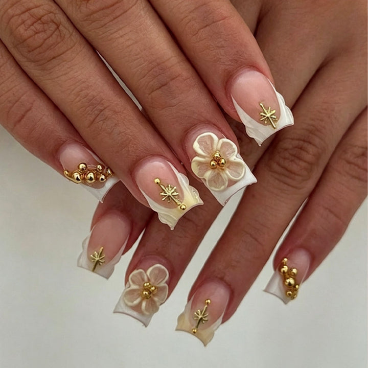 Kunstnagelset mit zarten Blüten- und Goldverzierungen Karnz