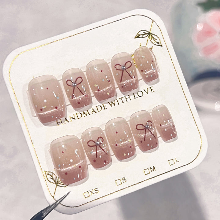 Künstliche Nagelkunst mit eleganten Schleifen und Glitzerakzenten Karnz