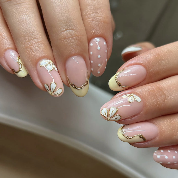 Kunstvolle Nagelverlängerungen mit floralem Design und eleganten Goldakzenten Karnz