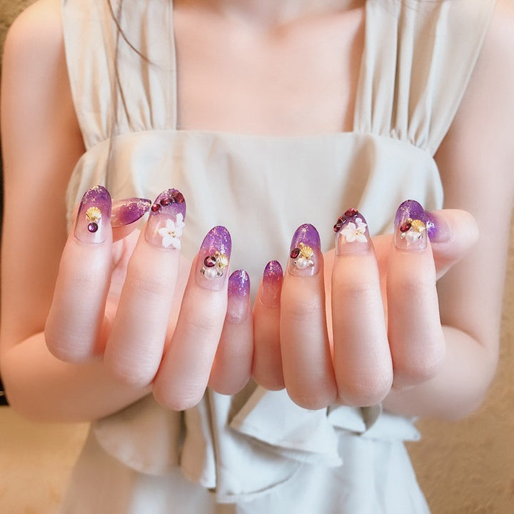 Künstlerisches Press-On-Nageldesign mit Glitzer und floralen Akzenten