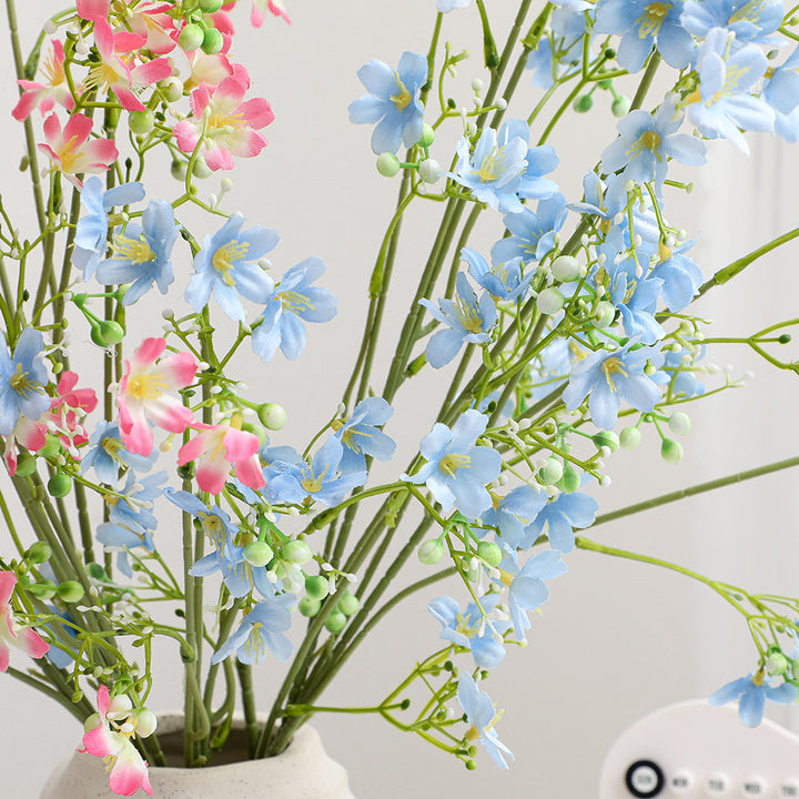 Künstlicher Blütenzweig mit zarten blauen Blumen und grünen Beeren Karnz