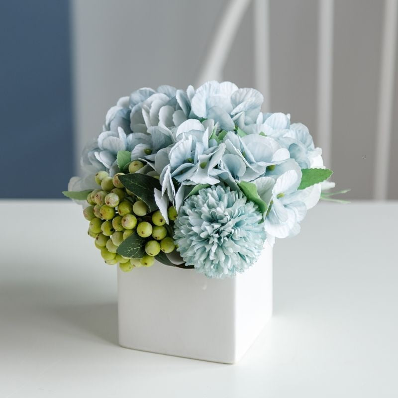 Lebensechte Blumenarrangement in dekorativem quadratischen Pflanzgefäß