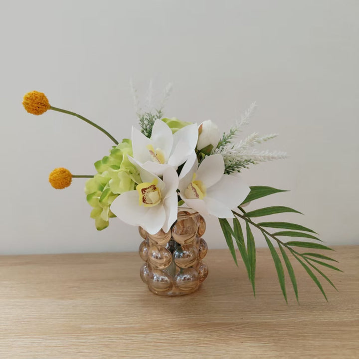 Lebensechte Blumenarrangement mit Orchideen und Grünpflanzen