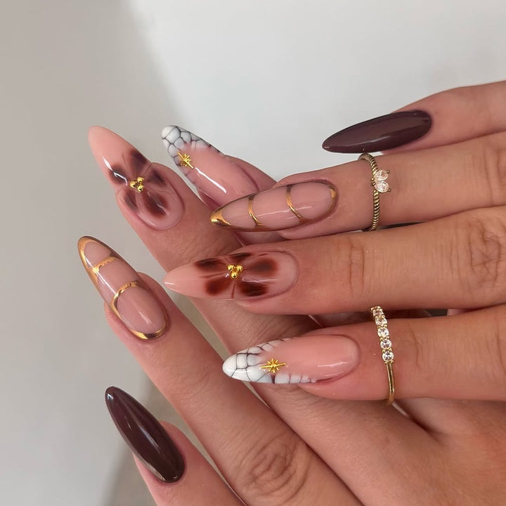 Kunstvolle Stiletto-Nägel mit Goldakzenten und dekorativen Blumenmotiven Karnz