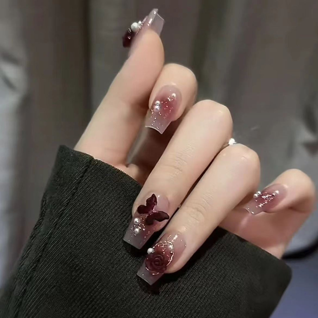 Kunstvolle Nagelkunst mit Schmetterlings- und Perlendetails Karnz