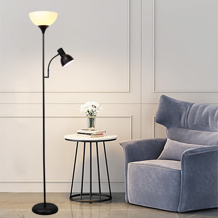 Stehlampe mit weißem Schirm und Leselicht neben blauem Sessel und rundem Beistelltisch