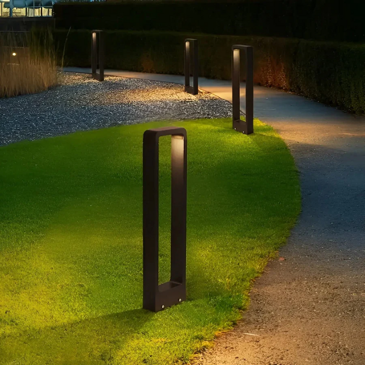 Reihe moderner LED-Pollerleuchten mit rechteckigem Rahmen entlang Kiesweg