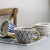 Tasse mit abstraktem geometrischen Muster und goldenem Henkel
