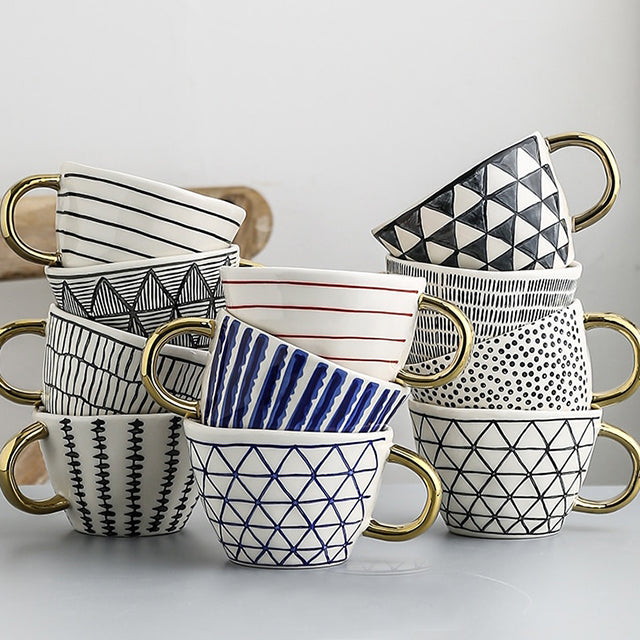 Tasse mit abstraktem geometrischen Muster und goldenem Henkel
